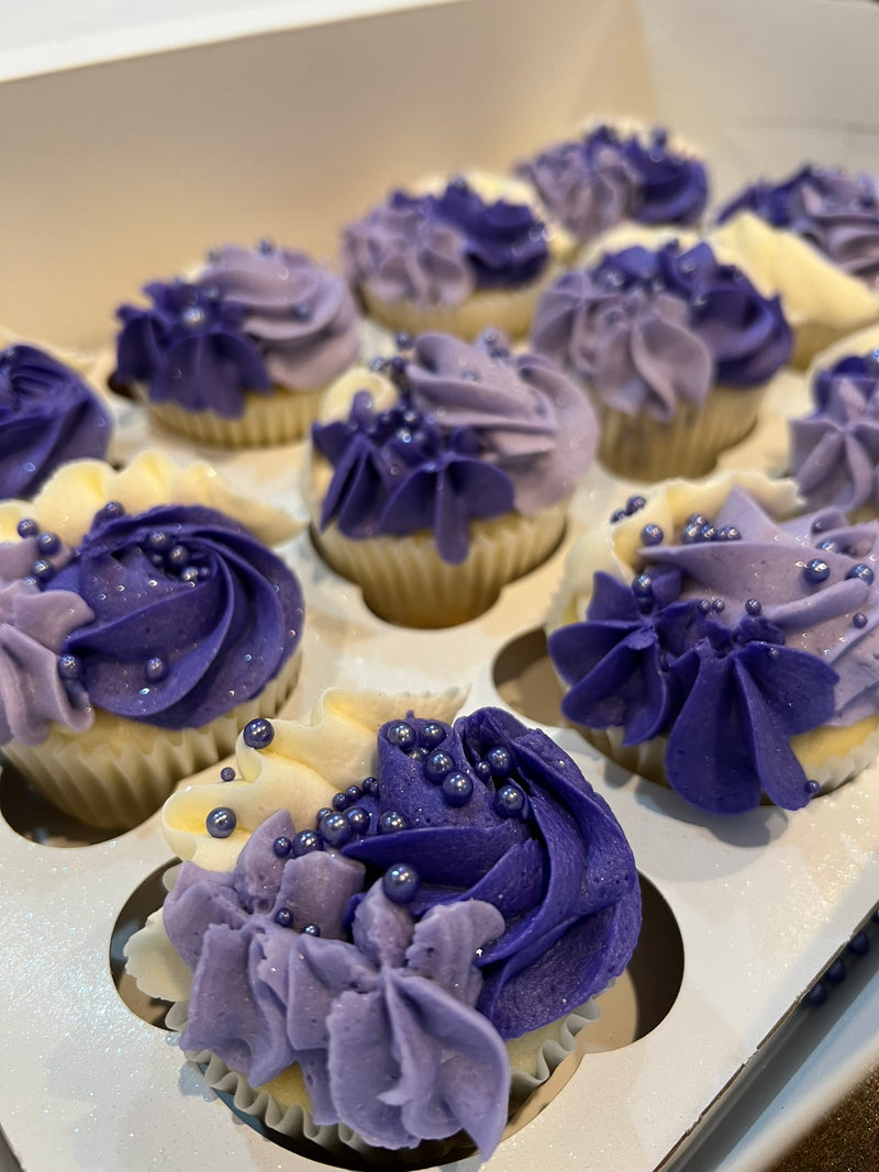 Cupcakes with purple frosting and decorative elements on a white surface