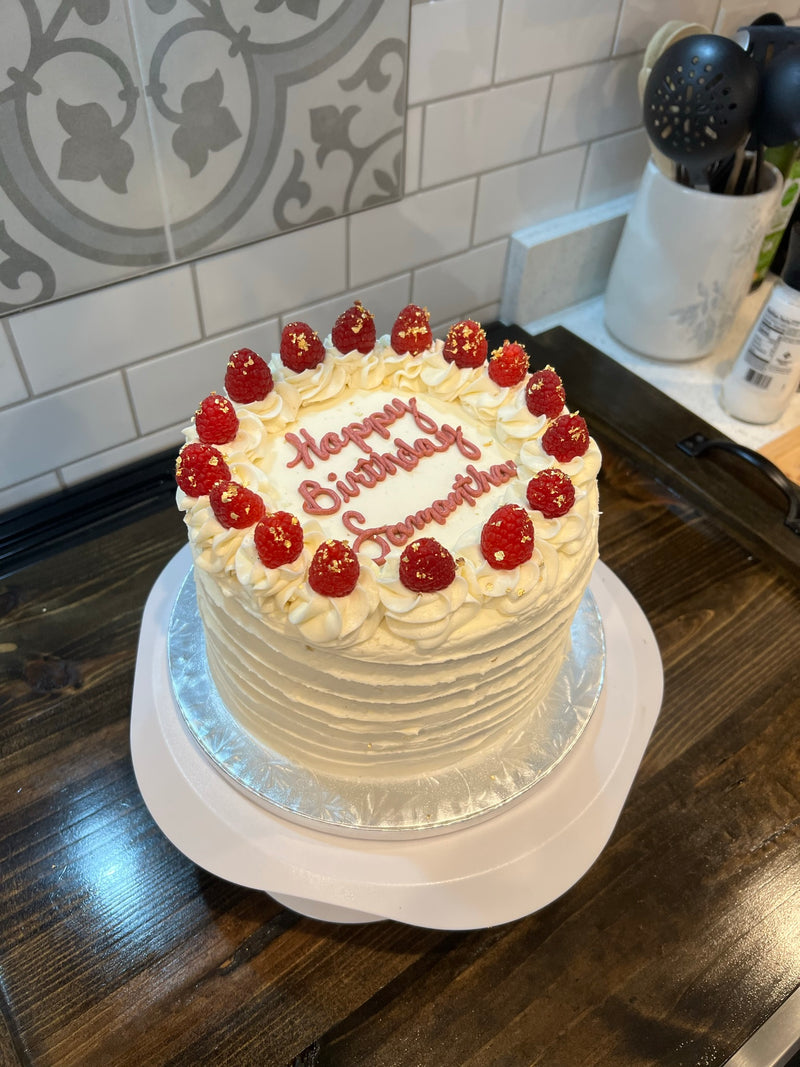 Birthday cake with rasberries on a wooden table