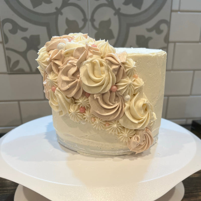 Decorative cake with intricate frosting on a white stand against a tiled wall background